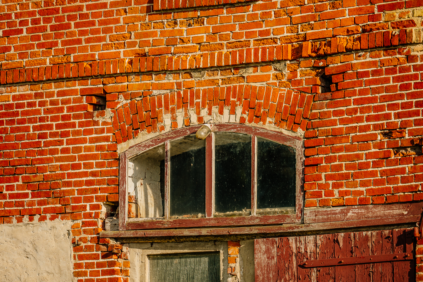 Altes Rundbogenfenster in der verwitterten Backsteinfassade eines Wirtschaftsgebäudes in Holzendorf.