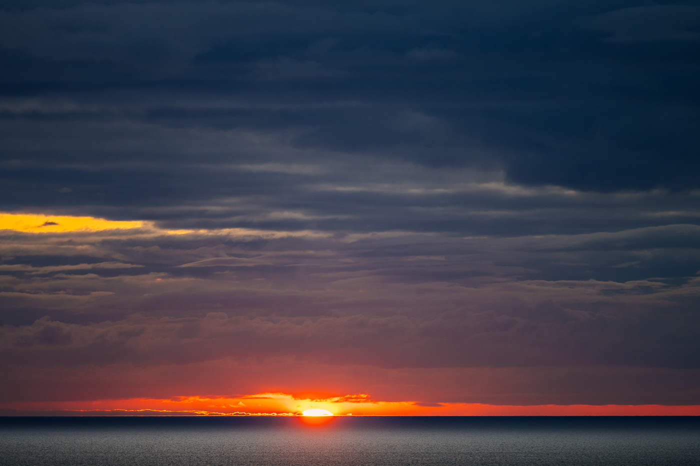 Sonnenaufgang über der Ostsee vor der Kreideküste im Nationalpark Jasmund auf Rügen unter dunklen Wolken. Sonnenaufgang über der Ostsee