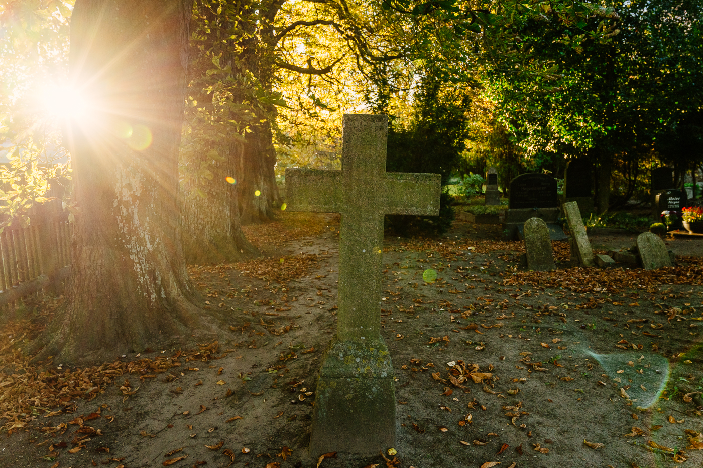Steinkreuz auf dem Friedhof in Landow auf Rügen im Gegenlicht der tief stehenden Herbstsonne. Steinkreuz auf dem Friedhof in Landow auf Rügen im Gegenlicht der tief stehenden Herbstsonne.