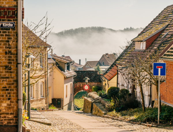Altstadt Sternberg, Blick durch die Straße Unter der Kirche auf Mühlentor mit Nebel über dem Sternberger See dahinter.