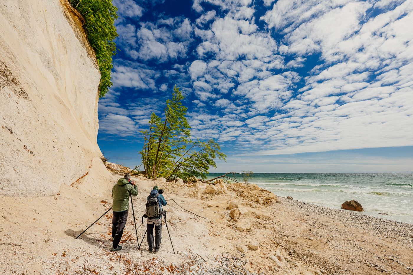 Zwei Fotografen stehen mit Stativen am Strand vor einem frischen Abbruch der Kreideküste im Nationalpark Jasmund auf Rügen.