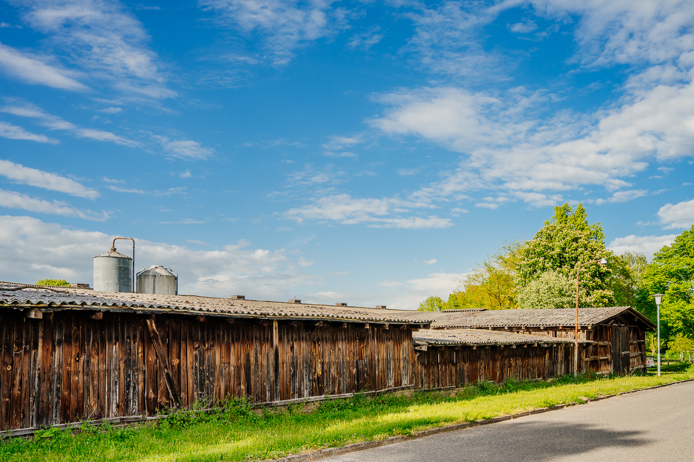 Lange hölzerne Wirtschaftsgebäude mit alten Silos im Hintergrund in Holzendorf.