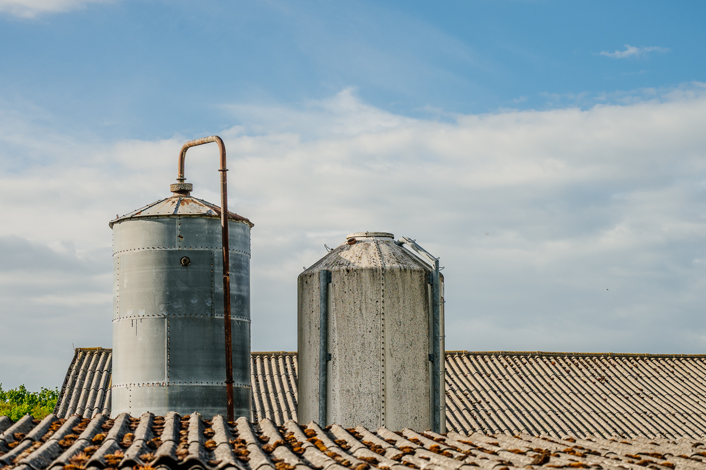 Zwei alte Metallsilos zwischen den Dächern landwirtschaftlicher Gebäude in Holzendorf.