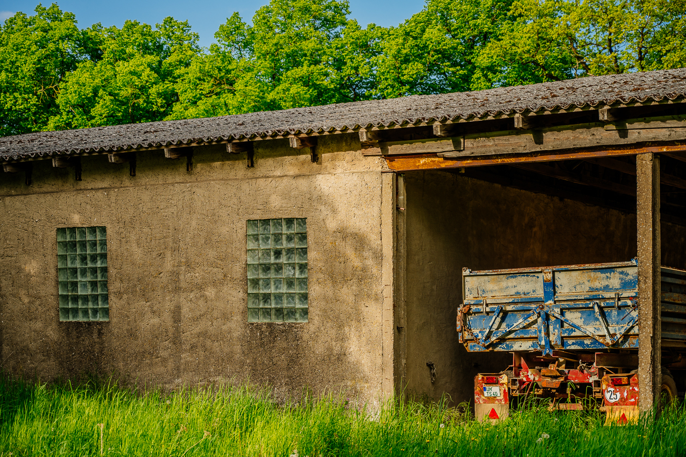 Alter blauer Landwirtschaftsanhänger in einem offenen Stallgebäude in Holzendorf.