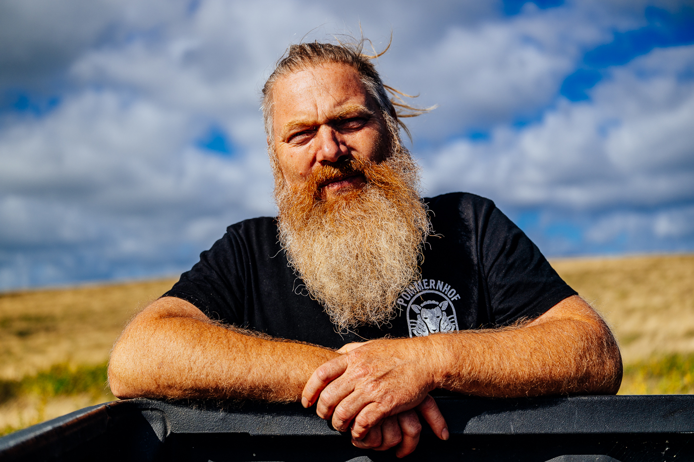 Porträt von Schäfer Frank Westphal auf den Zickerschen Bergen mit windbewegtem Haar und Bart vor spätsommerlichem Himmel.
