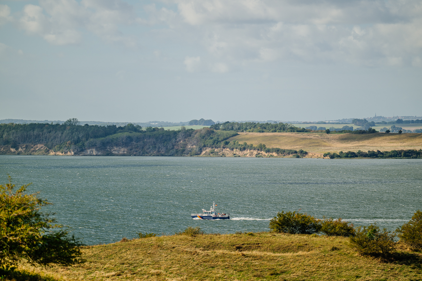 Ein Schiff der Küstenwache fährt über den Greifswalder Bodden, gesehen von den spätsommerlichen Höhen der Zickerschen Berge.