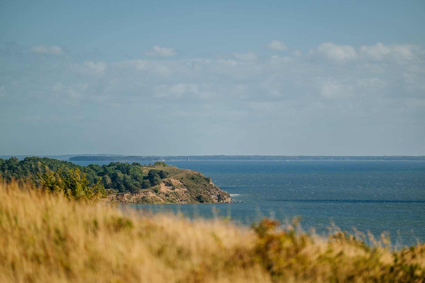 Blick von den Zickerschen Bergen über die Küste von Mönchgut bis zur Insel Ruden, deren kleiner Turm in der Ferne sichtbar ist.