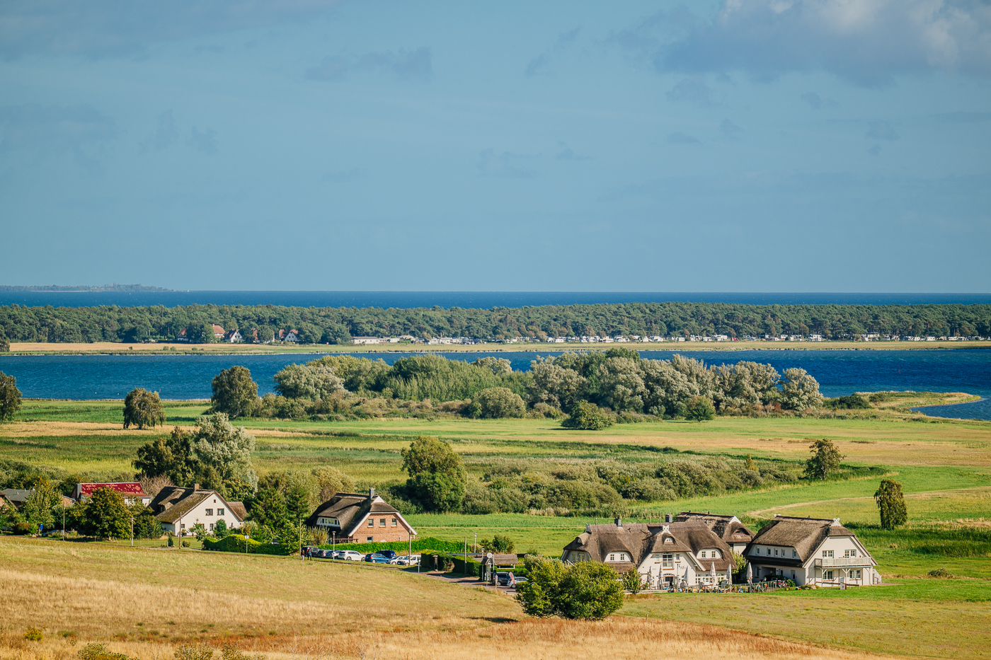 Weiße Häuser und Reetdächer von Groß Zicker zwischen Feldern und Wasser, gesehen von den Zickerschen Bergen auf Mönchgut.