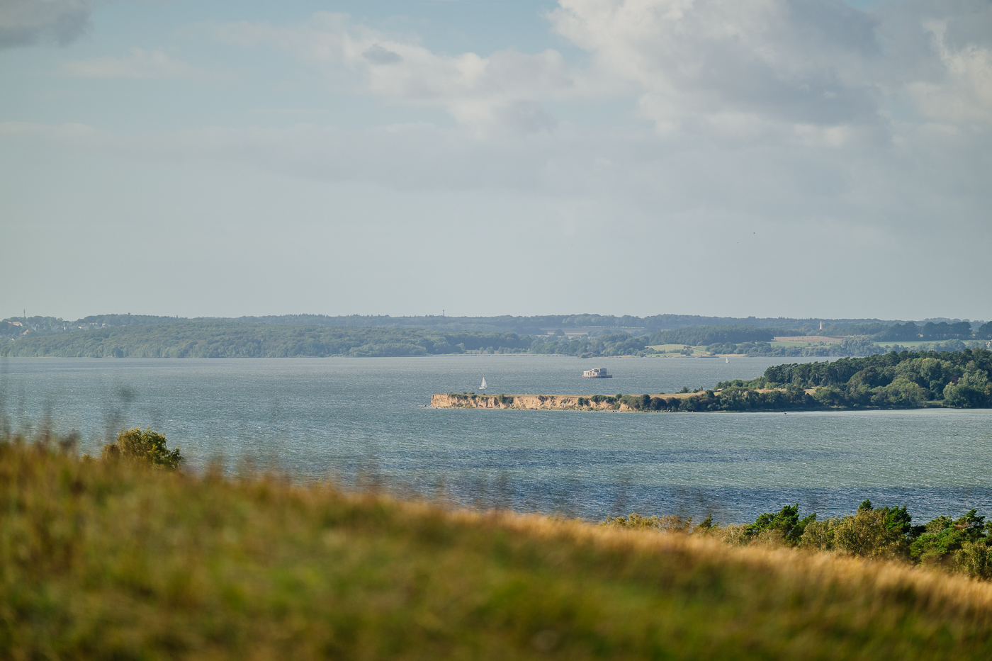 Weiter Blick von den Zickerschen Bergen über den Greifswalder Bodden, mit spätsommerlichen Hängen und Küste in der Ferne.
