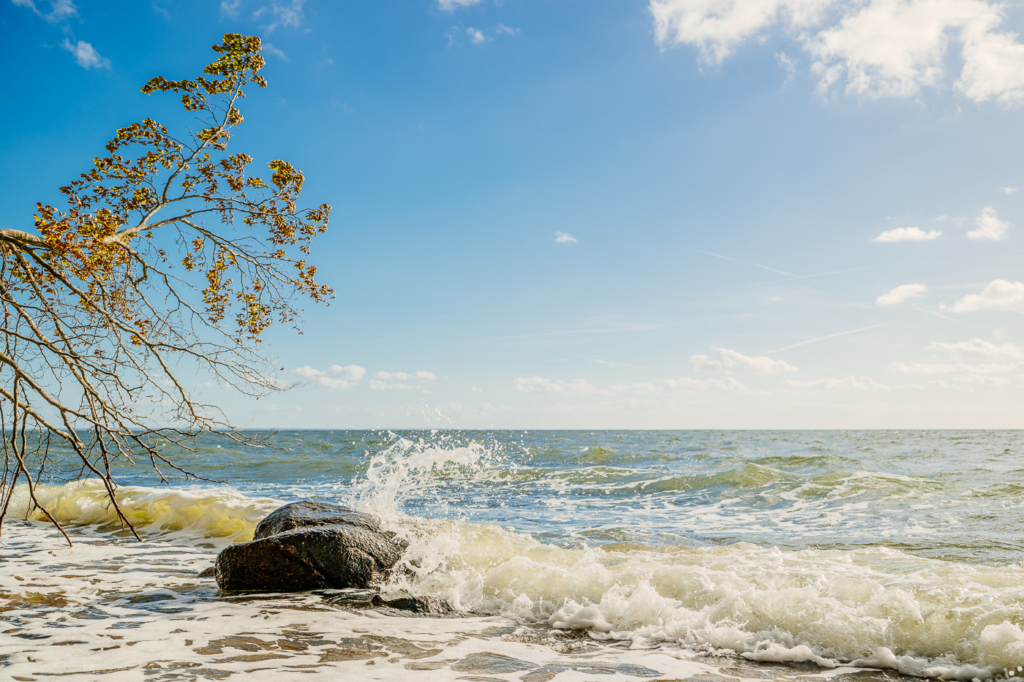 Wellen schlagen am Strand unterhalb der Zickerschen Berge auf Mönchgut gegen einen großen Findling.